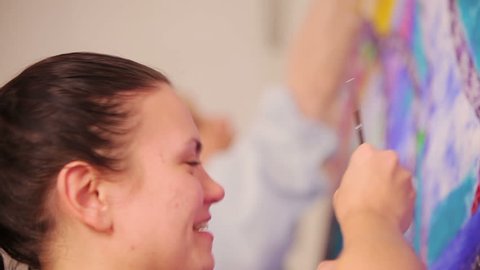  Girl artist painting with paintbrush and smiling