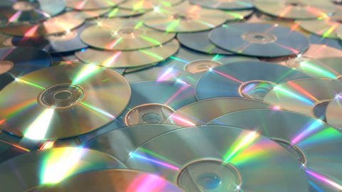 Sliding right dolly shot of over a pile of discs, DVDs and CDs