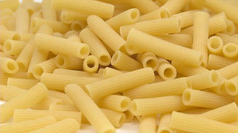 rigatoni pasta falling on white background and filling the screen in slow motion