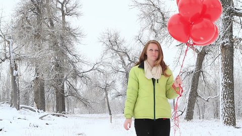 Teenager girl with red balloons walking in the park.