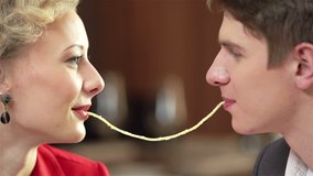 Close-up of a romantic couple eating spaghetti together and kissing