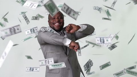 Slow-motion of an African-American businessman dancing among falling dollar bills in slow motion