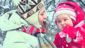 Beautiful Winter Family having fun outdoors. Happy laughing mother with her little baby girl playing in Winter park. Snow. Slow motion video footage 240fps. Slowmo 1080p