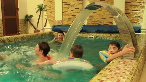 happy parents and children swim in a small pool
