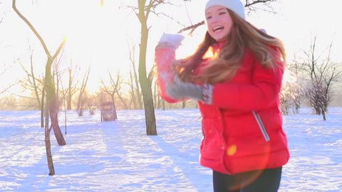Sunny Winter Joyful Girl Throwing Snow. Happiness. Young Couple throwing a snowballs outdoors. Laughing People having fun in winter park. Slow motion video footage 240fps. Slowmo