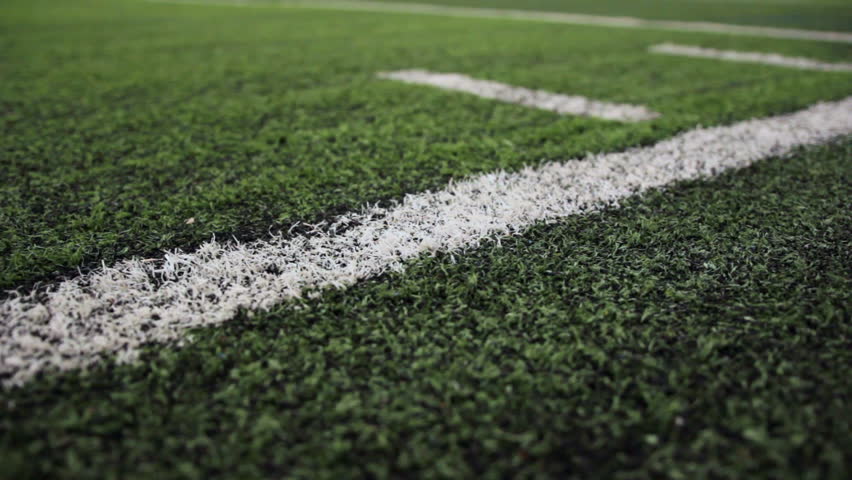 Close up of the out of bounds line on a turf football field. 