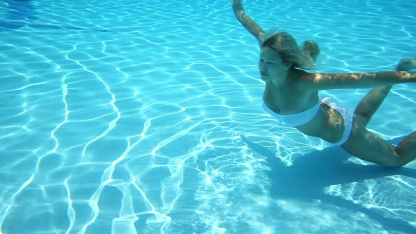 Beautiful girl in swimsuit swim under water in blue pool
