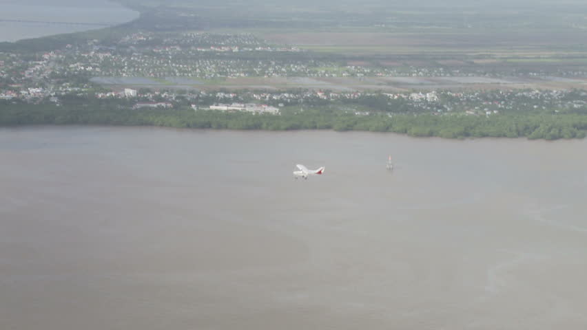 Plane flying over river and city in Guyana