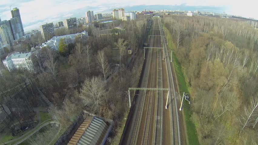 Cityscape with four railroad tracks between park forest and houses