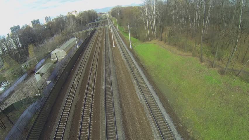 Railroad tracks near city buildings at autumn sunny day