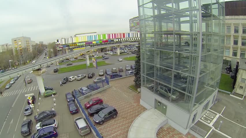 Multilevel parking with glass walls and road traffic near edifice of telecentre
