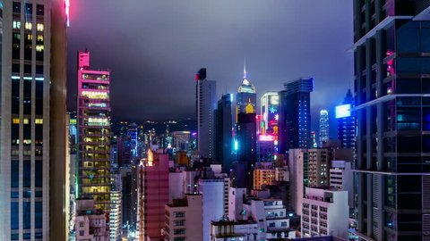 City Night Timelapse.  Wide Zoom In. Attractive Hong Kong night timelapse. Commercial office buildings, commercial LED flashing billboards and residential buildings. Fast moving cloud on the sky. 