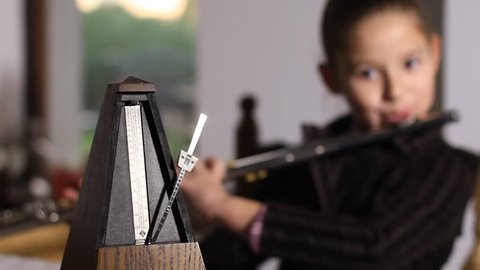 The little girl plays flute. Detail view on metronome and on her. Pull focus.