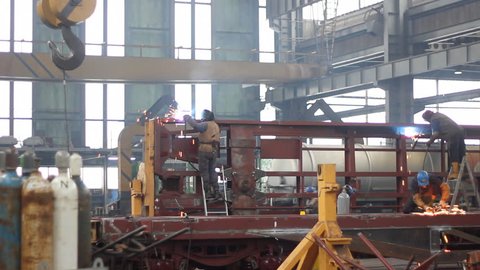 Steel workers welding, grinding, cutting in metal industry. Factory for the production of wagons