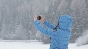 Young woman uses a smart phone to video a beautiful view in winter scenery