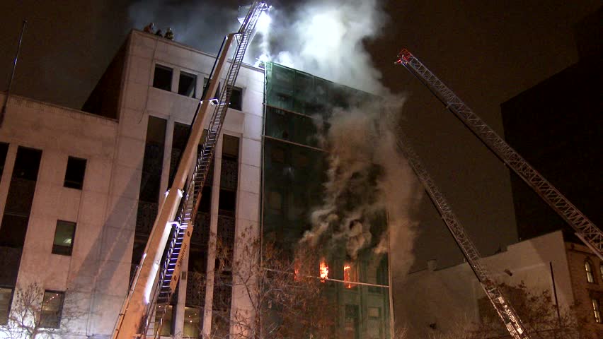 MONTREAL, QC - 1/2014 - 4K 60fps - Steady shot of fire & ladders. Tripod mounted shot of building on fire with firemen on the roof with flames and multiple ladders and fire trucks.