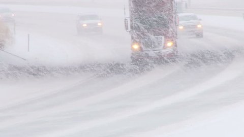 Traffic driving along freeway during intense snow storm.