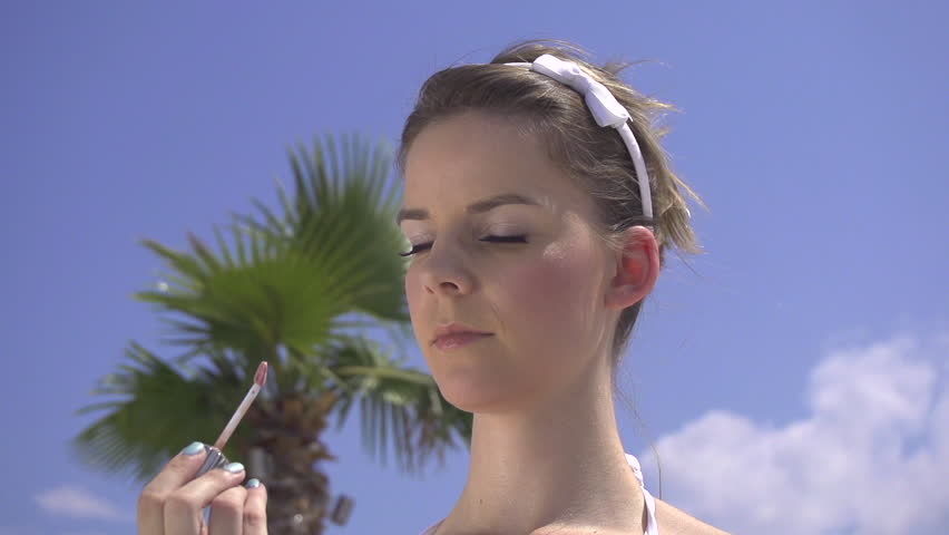 SLOW MOTION: Young woman applying lip gloss