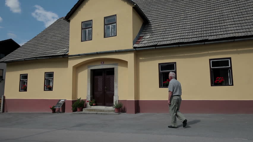 Old man enters a building with two floors