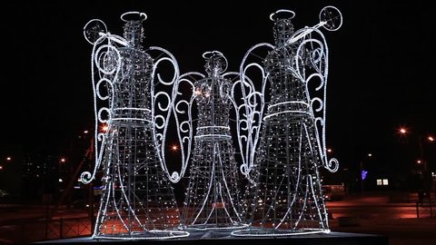 luminous figures of the three angels in the night city loop