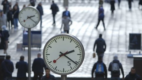 Commuters and Bankers walk past the Six Public Clocks on Reuters Plaza, Canary Wharf