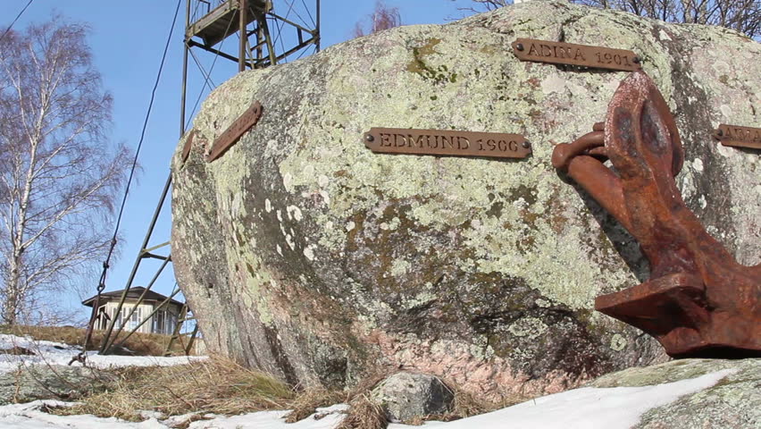A rock with name tags and an old rusty anchor on it