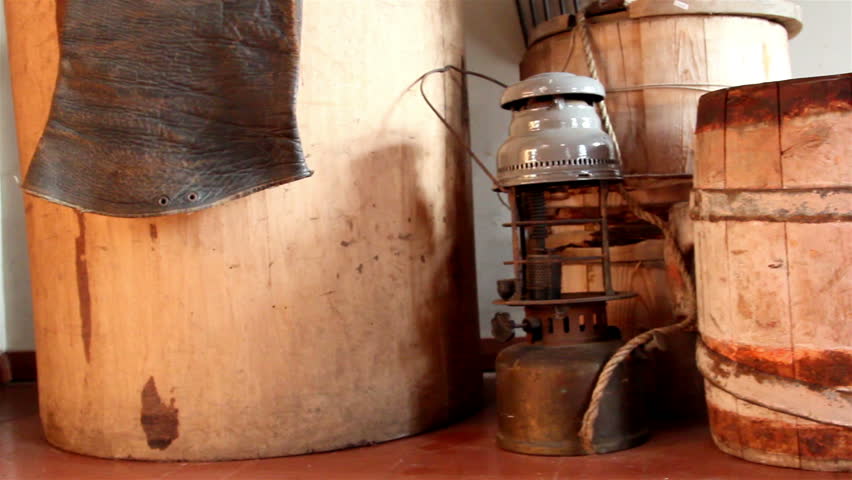 Three wooden barrels and an old lamp with chairs and ropes placed inside a room