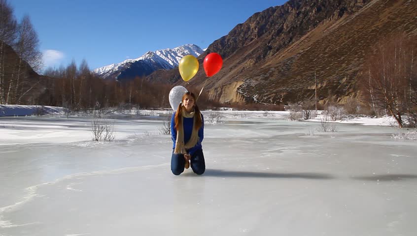 Cheerful happy girl sitting and laughing with hair balls on ice 