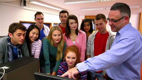 Front view of group of Caucasian computer lecturer pointing something out to his class on the screen at the university