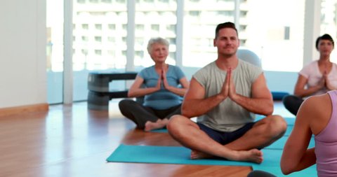 Yoga class sitting in lotus position together at the gym