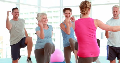 Aerobics class stepping and laughing together at the gym