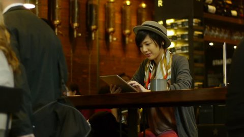 Young Asian Woman With A Digital Tablet At A Busy Coffee Shop / Restaurant