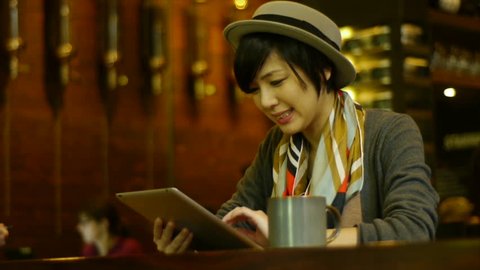Attractive Young Woman Busy On Her Digital Tablet At A Nice Coffee Shop / Restaurant