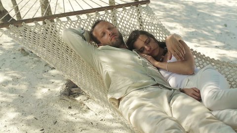 Young couple sleeping on hammock on the beach
