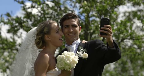 Bride and groom taking a selfie outside on their wedding day – Stockvideo