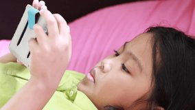 Asian girl plays games by mobile phone on the bed