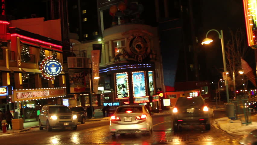 Night drive at Clifton Hill District towards Falls Ave., Niagara Falls with view of Hard Rock Cafe on the left and Rainbow Bridge on the right.