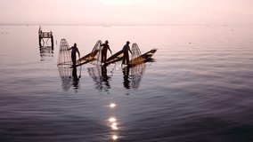Myanmar, Burma Inle Lake fishermen fishing on traditional boat at sunset. Beautiful reflection of evening sun and silhouettes in water. Famous tourist travel destination 4k ultra high definition video