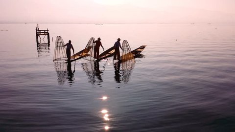 Myanmar, Burma Inle Lake fishermen fishing on traditional boat at sunset. Beautiful reflection of evening sun and silhouettes in water. Famous tourist travel destination 4k ultra high definition video : vidéo de stock