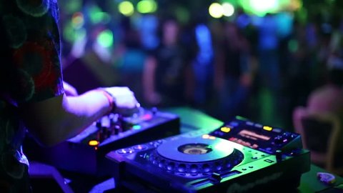 Hands of DJ which mixes music tracks with CD-players and mixer in nightclub