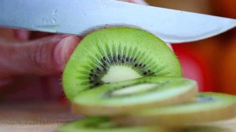 Hand slicing a kiwi  with a knife, close up, HD 1080P