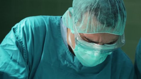 Surgeon close up face.Surgeon performing operation in hospital operating room.Surgeon wearing surgical mask and hat.Surgeon operate patient.