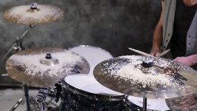 Drummer plays drums covered snow in gray room at studio