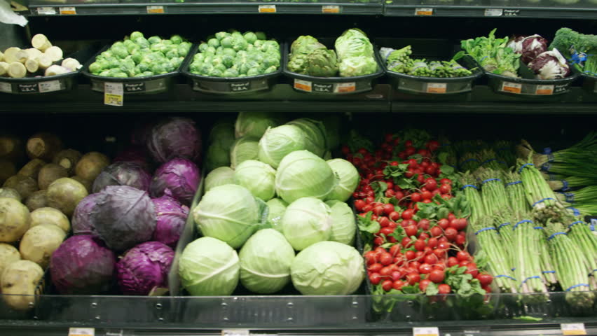 Medium shot moving past fresh vegetables in a supermarket grocery. Includes cabbage, celery, broccoli, lettuce, carrots, corn, onion, etc. Wide shot and close-up of same set-up are in my portfolio. Royalty-Free Stock Footage #5695409