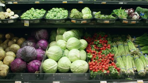 Medium shot moving past fresh vegetables in a supermarket grocery. Includes cabbage, celery, broccoli, lettuce, carrots, corn, onion, etc. Wide shot and close-up of same set-up are in my portfolio.