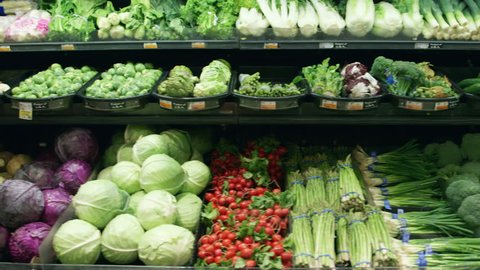 Wide shot moving past fresh vegetables in a supermarket grocery. Includes cabbage, celery, broccoli, lettuce, carrots, corn, onion, etc. Medium shot and close-up of same set-up are in my portfolio.