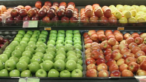 Tracking (dolly) shot moving past fruit in a supermarket grocery.  Includes red apples, green apples, lemons, etc.