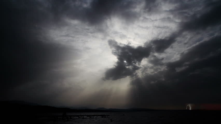 Coming Storm. Time laps. Clouds cover the sun over the sea. Near the horizon lightning flashes