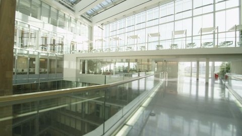 Interior view of a large contemporary office building with glass partitions and large central atrium. No people.