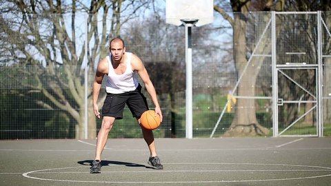 Portrait of a basketball player dribbling the ball with skill on an outdoor basketball court: stockvideo